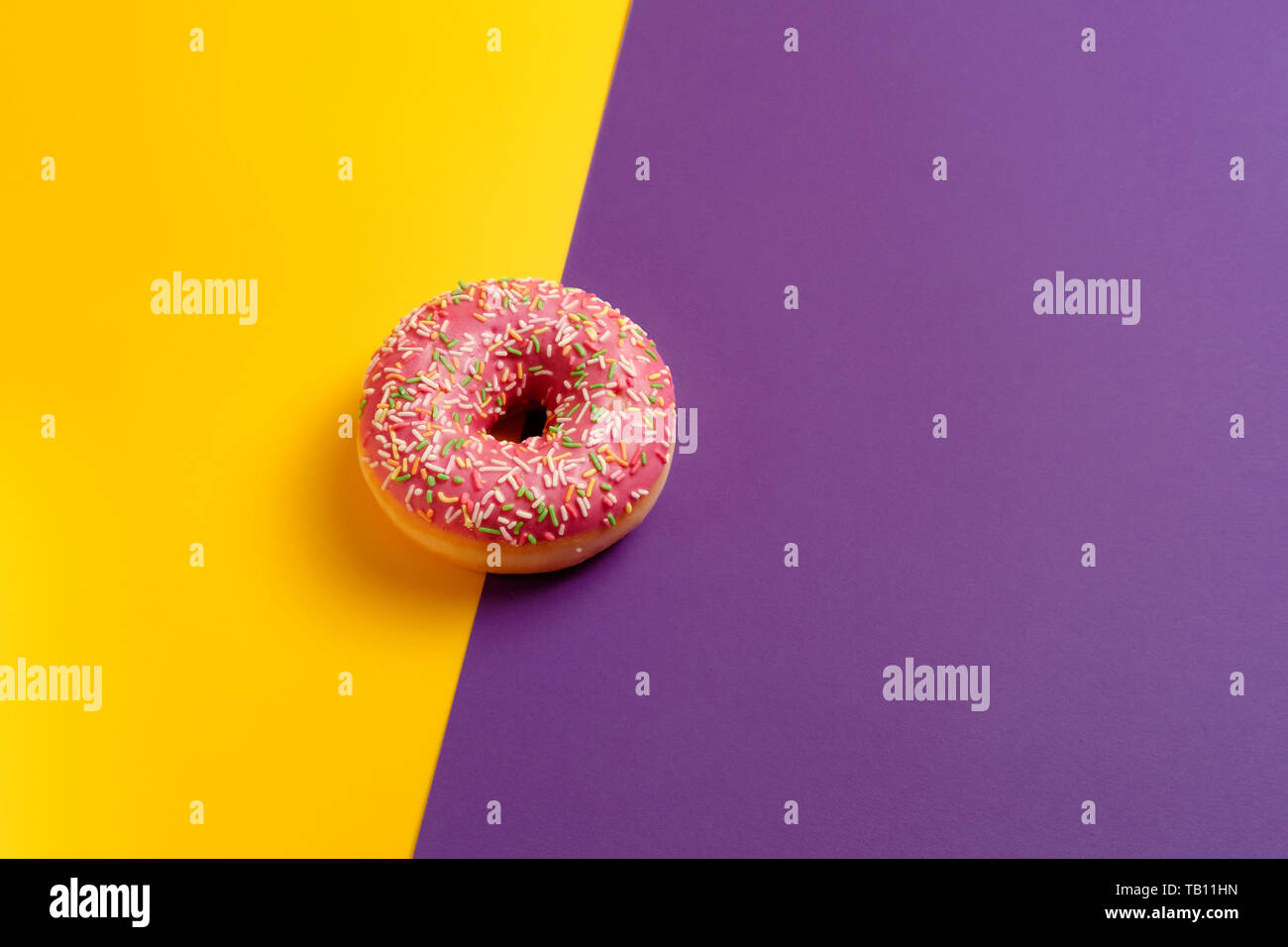 pink donut on yellow and violet deep purple background top view copy ...