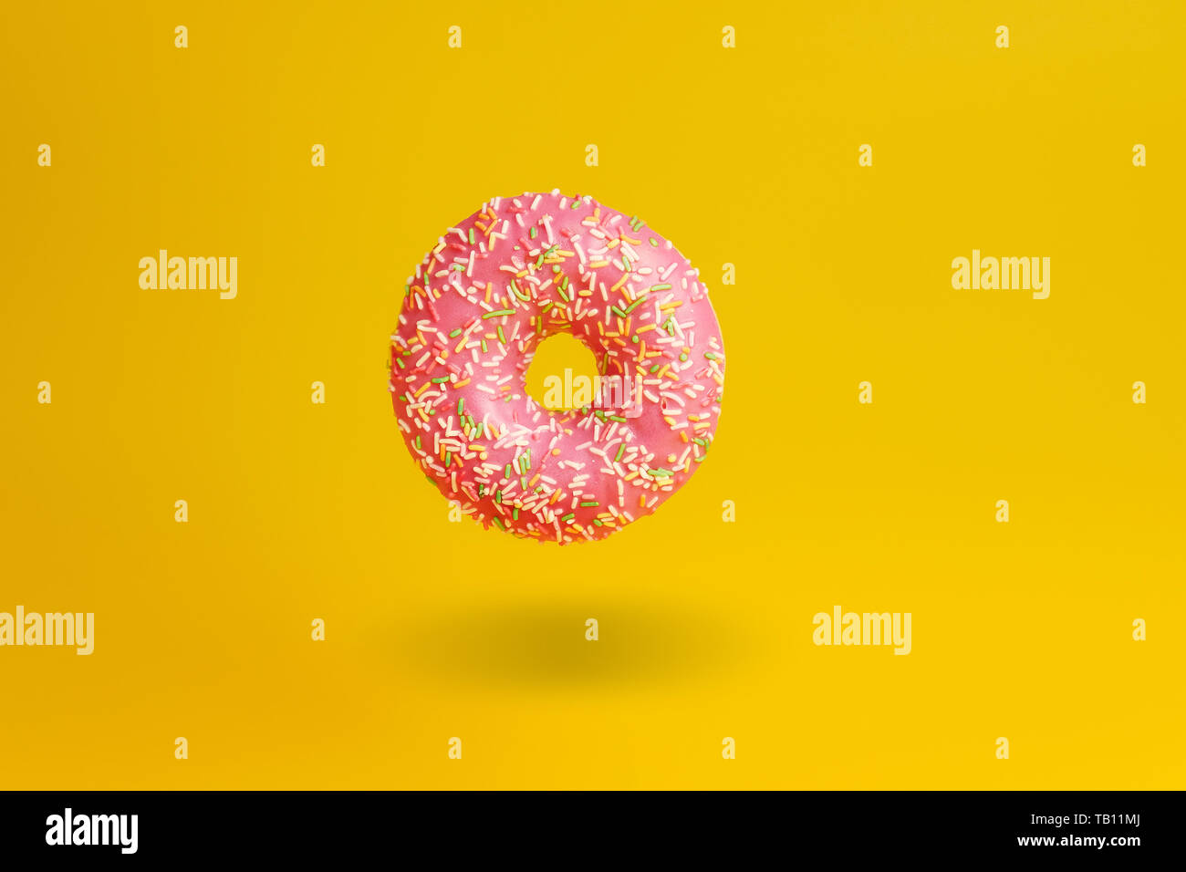 pink donut on yellow background with shadow Stock Photo