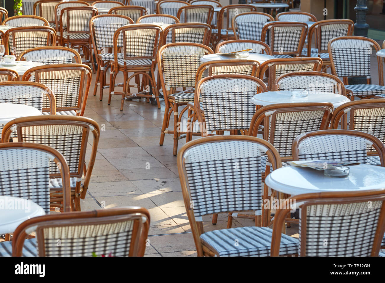 Outdoor cafe tables and chairs in a sunny summer day Stock Photo