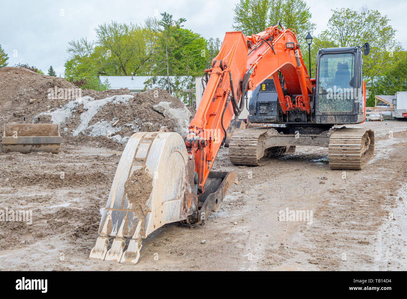 Dirty orange excavator parked at a construction site. Stock Photo