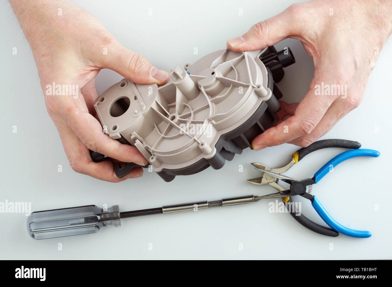 Old elderly home craftsman repairs the gearbox from electric meat