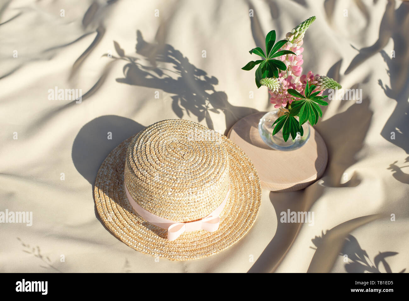 Straw hats lay on a white picnic blanket at green lawn bright summer ...