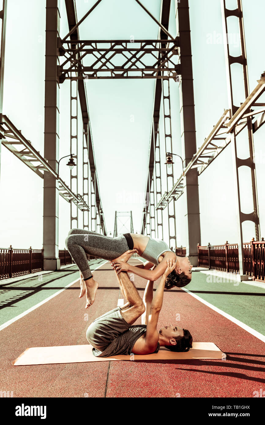 Yogi supporting his partner while doing acroyoga outdoors Stock Photo