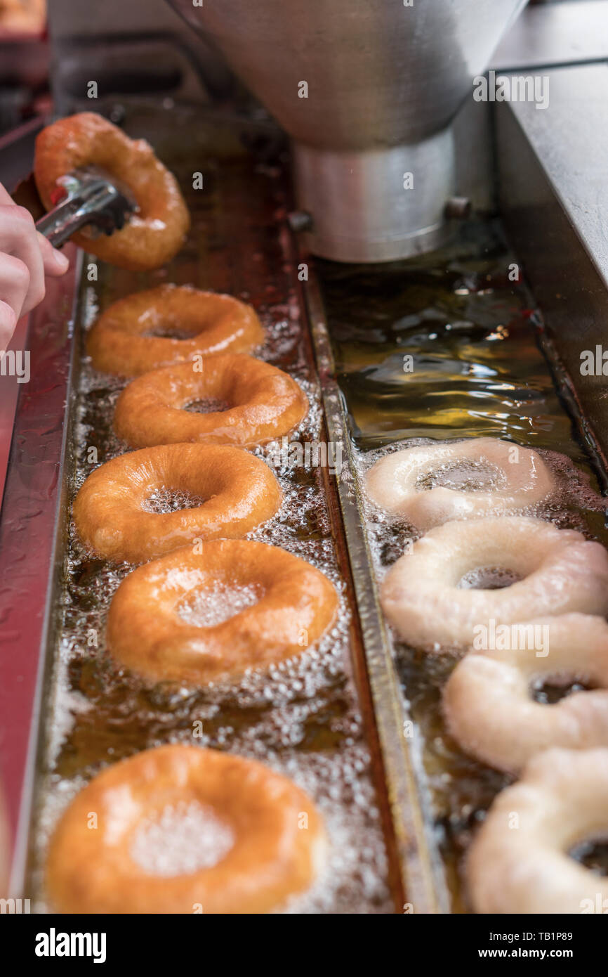 Donut making machine frying donuts in hot oil. Unhealthy junk food