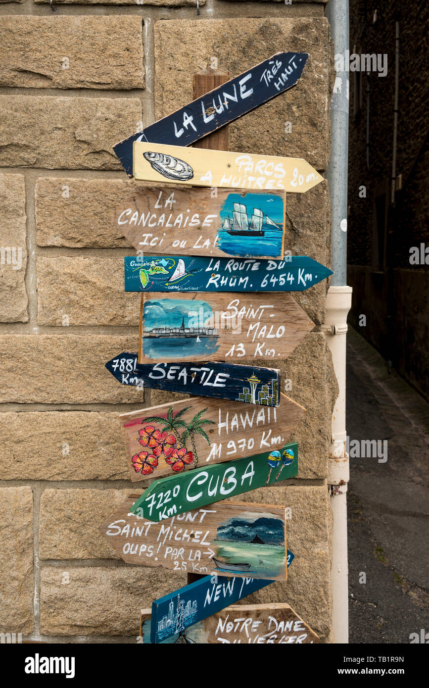 Signpost showing directions to various world famous destinations including moon, Cancale, Brittany, France Stock Photo