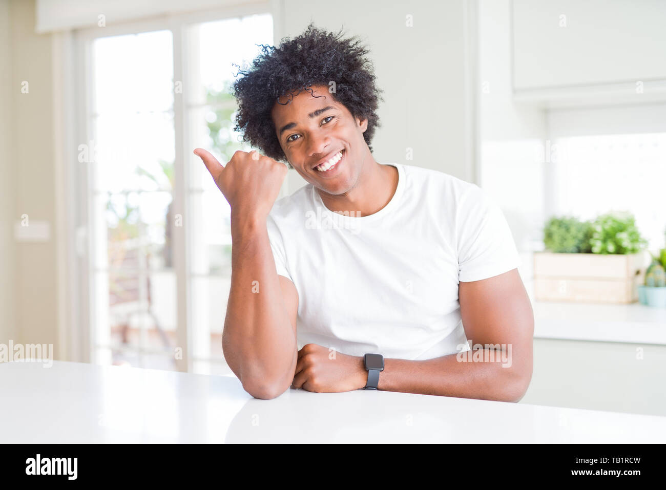 Young african american man wearing casual white t-shirt sitting at home ...