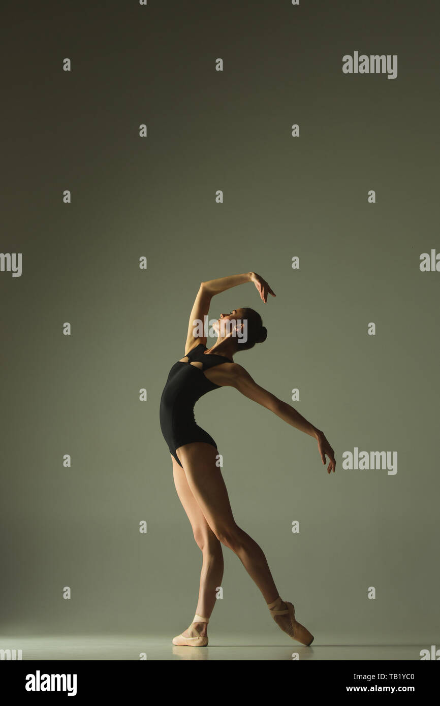 Graceful ballet dancer or classic ballerina dancing isolated on grey Graceful ballet dancer or classic ballerina dancing isolated on grey