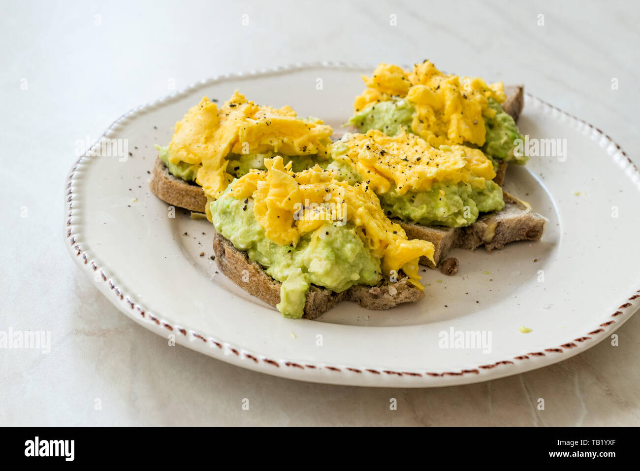 Scrambled Eggs with Avocado on Toast Bread for Breakfast. Organic Food. Stock Photo