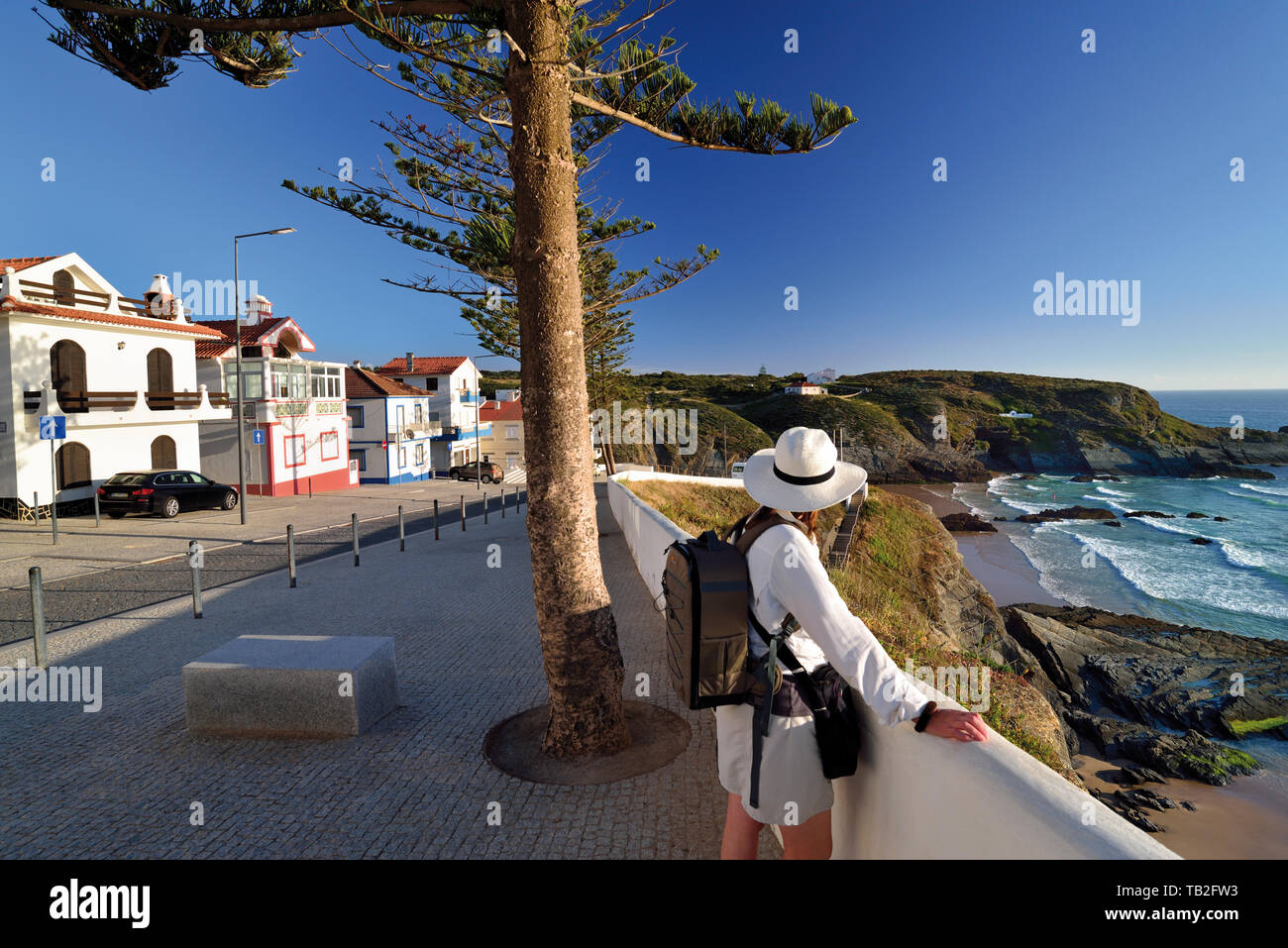 Woman with hat and backpack looking to wild rocky bay in fishermen´s village Stock Photo