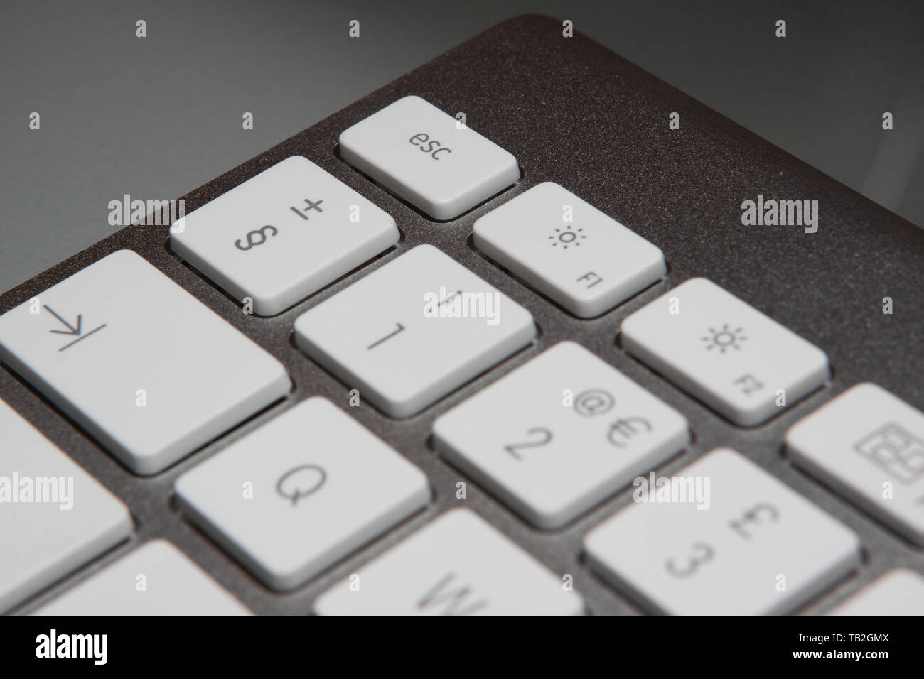 Apple iMac keyboard on an office desk focusing on the escape key. Stock Photo