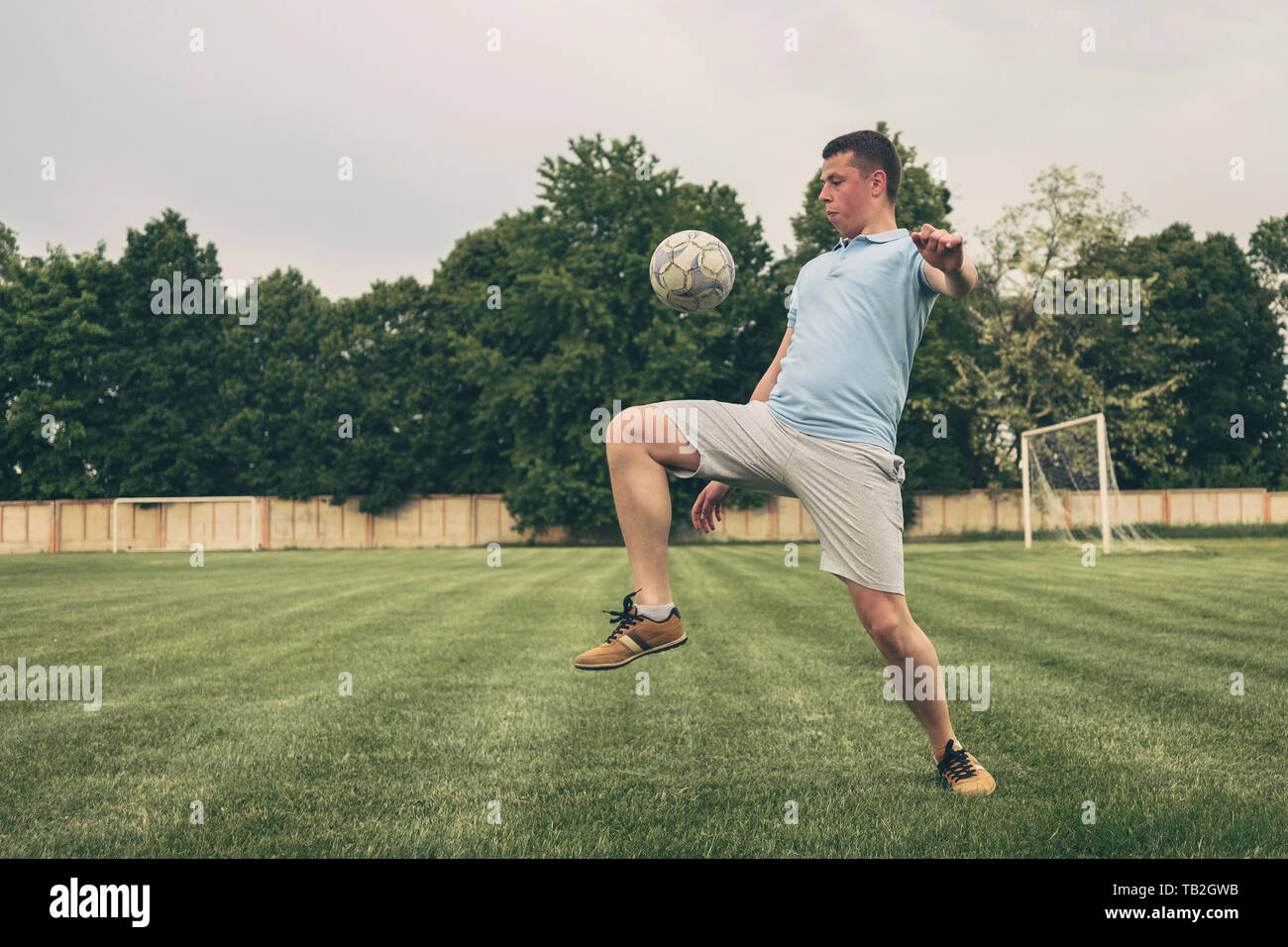 Young player practicing ball control with a soccer ball bouncing it on his upper leg during training fro a game or competition on a sports field Stock Photo