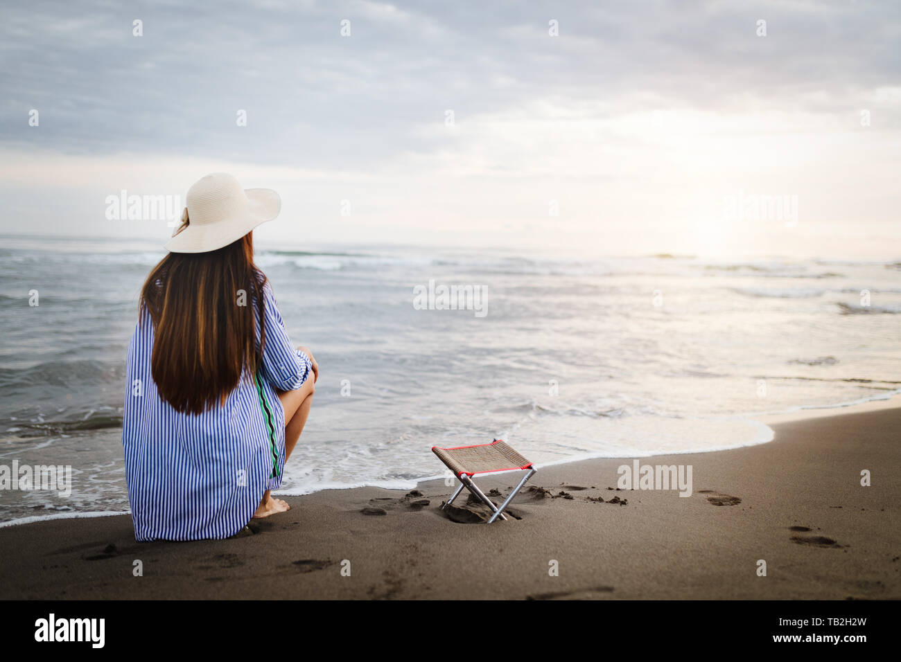 Calm woman sitting alone on a sand evening beach Stock Photo