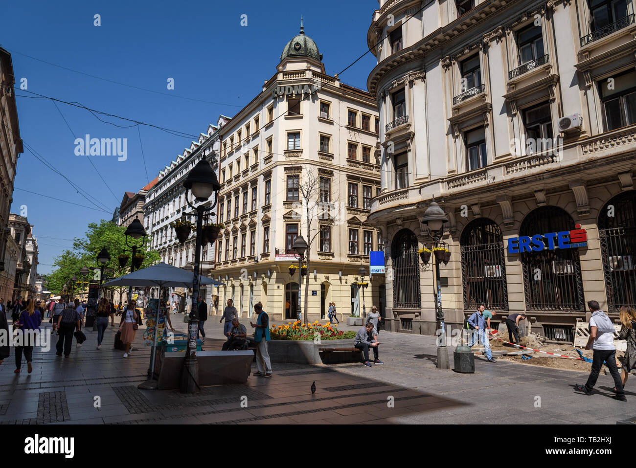 Belgrade, Serbia - April 19, 2018. People walking in Knez Mihailova street. City scene in old town with building facades, green trees and spring bloom Stock Photo