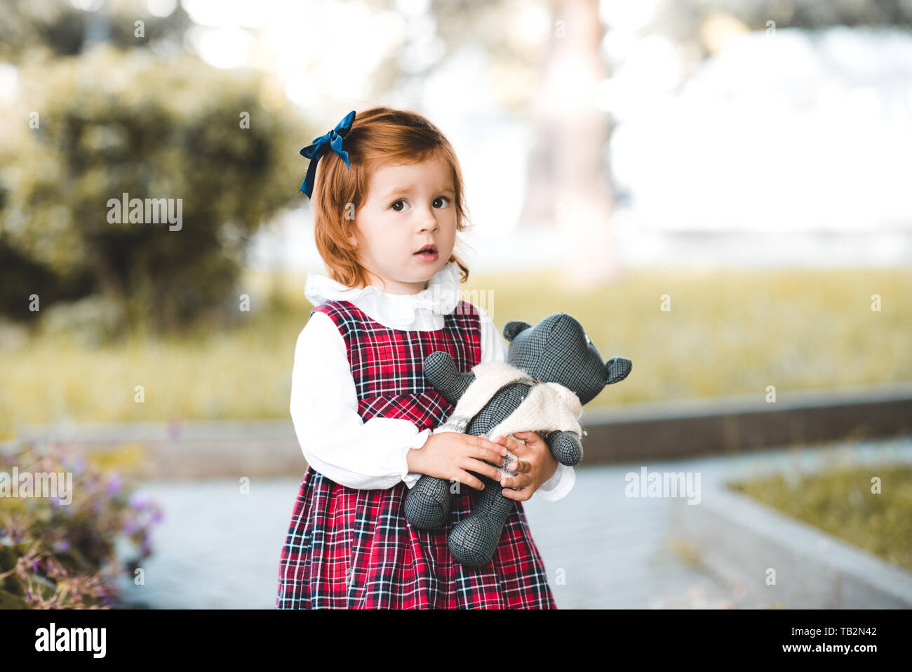 Cute baby girl 1-2 year old holding teddy bear outdoors. Looking at camera. Childhood. Stock Photo