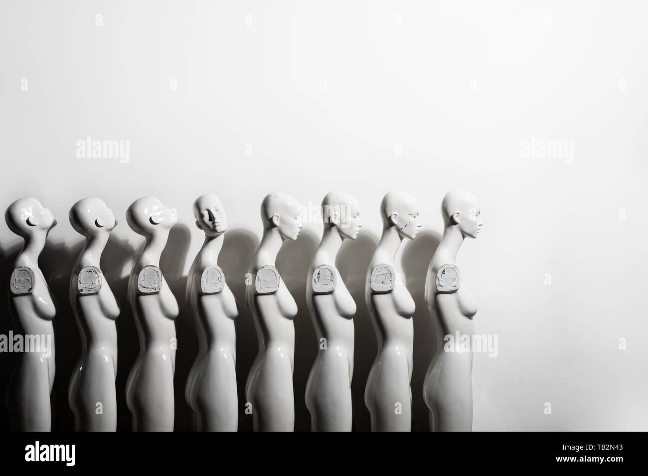 White Woman Torso Figurines Standing in The Line All Looking to Same Direction except of One, Shoot on White Background With Space for Text. Stock Photo