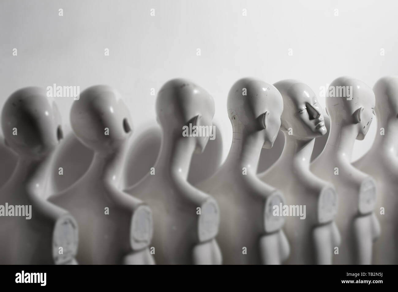 White Woman Torso Figurines Standing in The Line All Looking to Same Direction except of One all shoot on White Bright Background Stock Photo