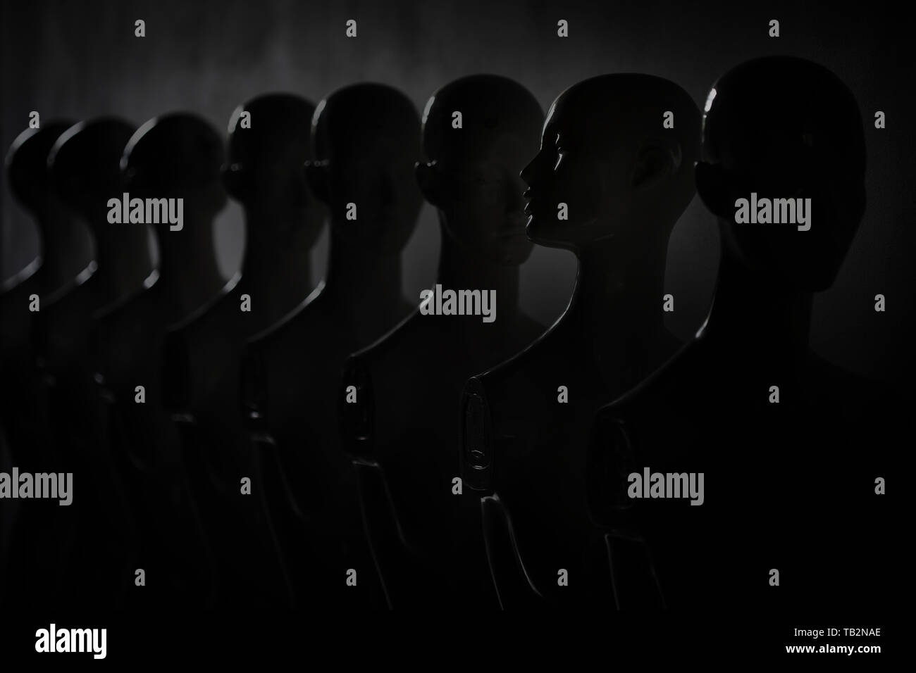 Dark Depressive Picture of Plastic Woman Mannequins Standing in The Line, With One Looking to Another Direction then the Others Stock Photo