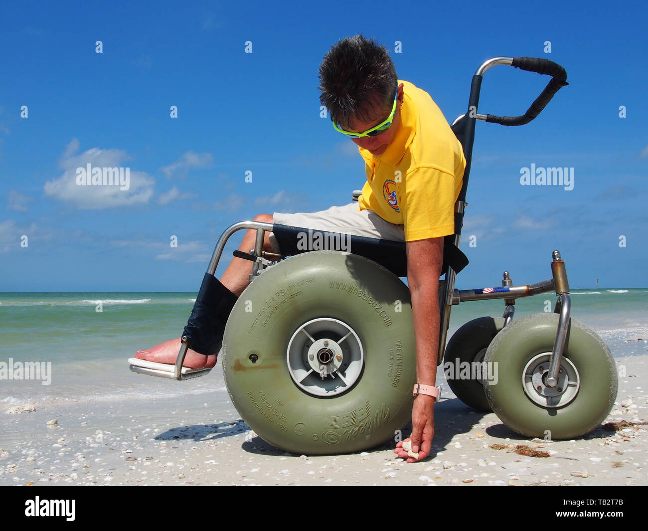 Disabled woman in beach wheelchair enjoys the sun and sand at Honeymoon Island State Park in