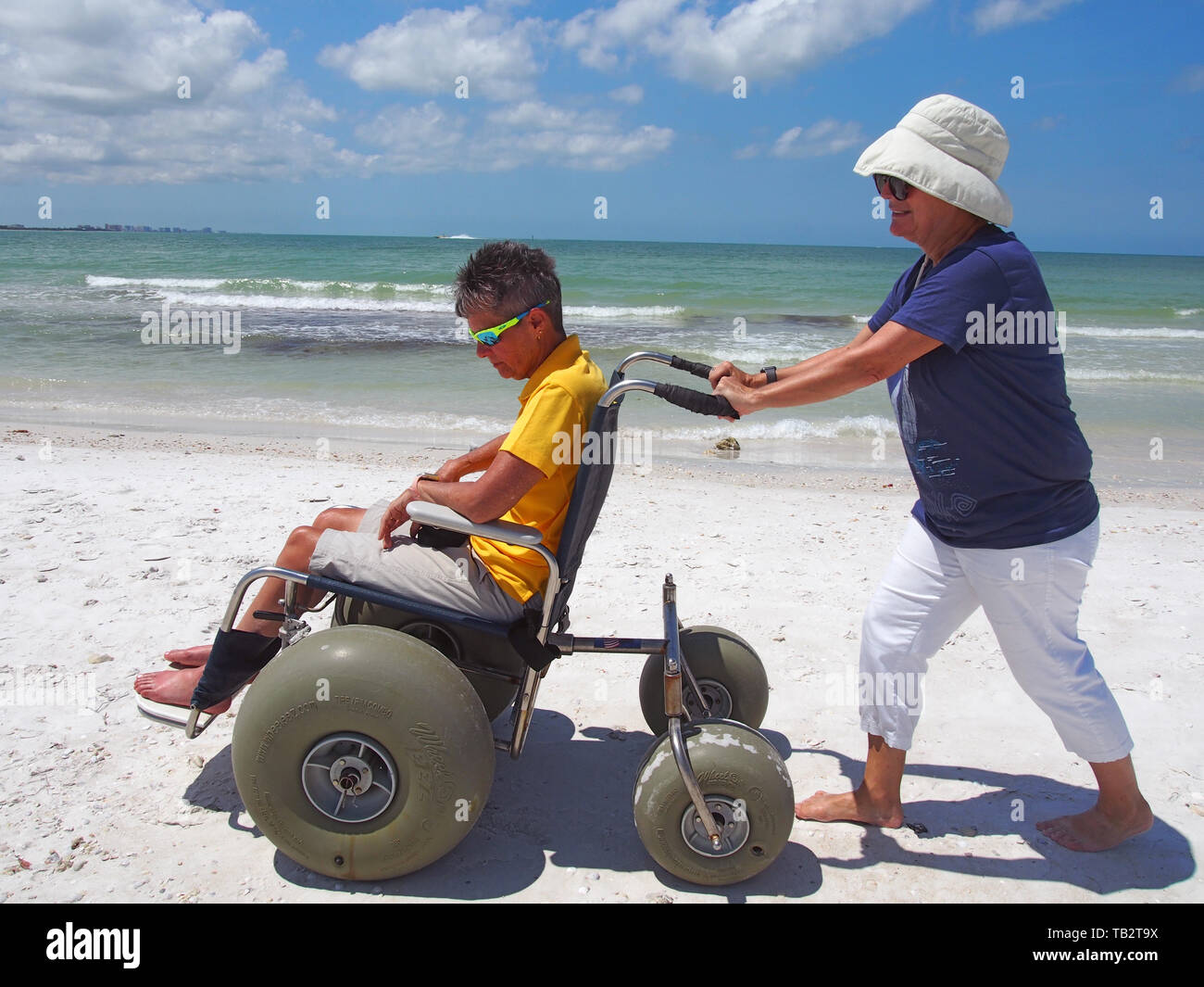 Disabled woman in beach wheelchair enjoys the sun and sand at Honeymoon Island State Park in