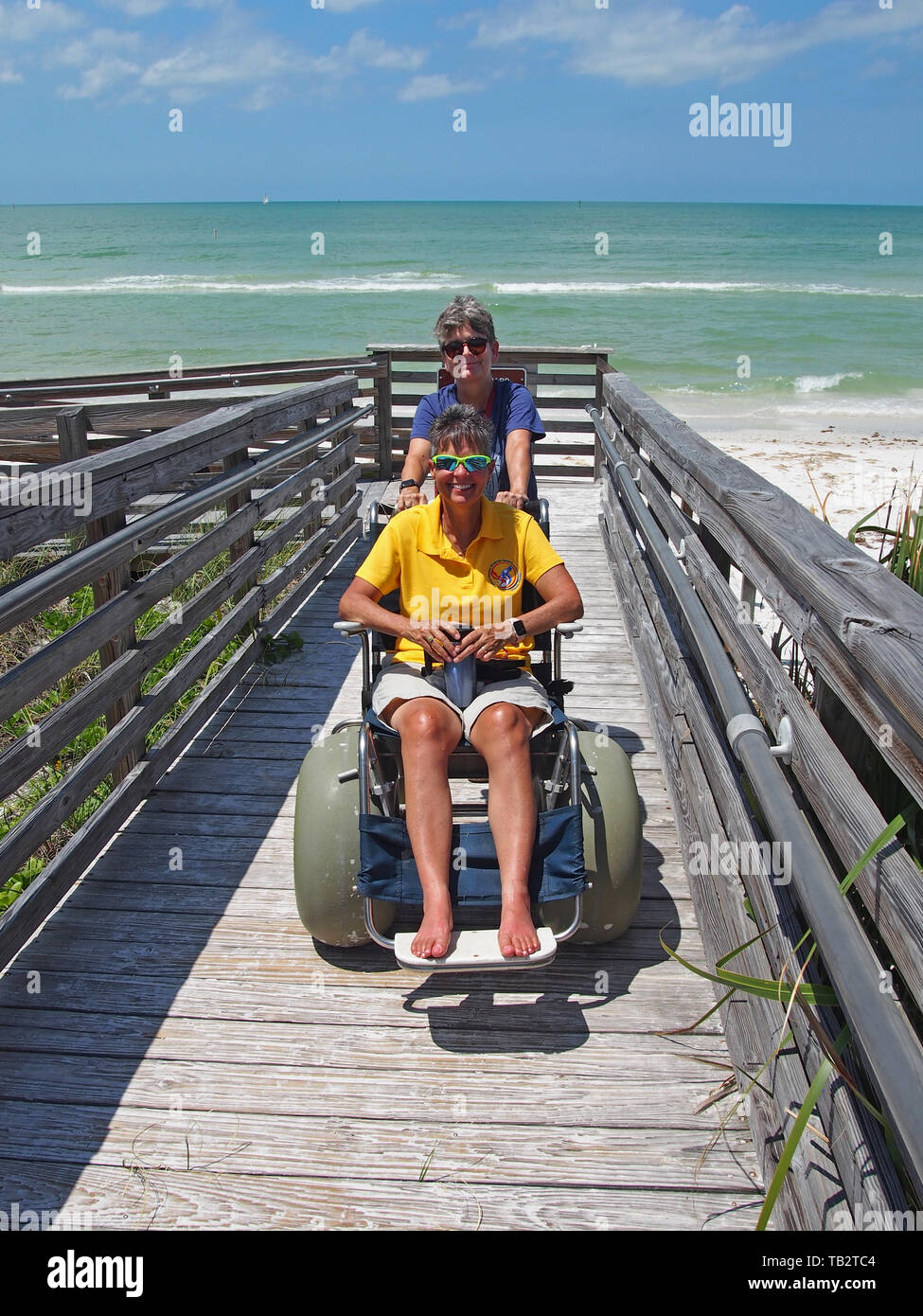 Disabled woman in beach wheelchair enjoys the sun and sand at Honeymoon Island State Park in