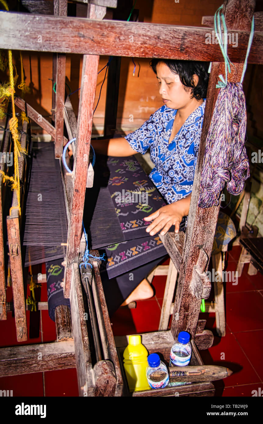 BALI, INDONESIA - FEBRUARY Circa, 2019. Unidentified mature indonesian woman making a traditional hand made carpet in factory. Each carpet can take mo Stock Photo