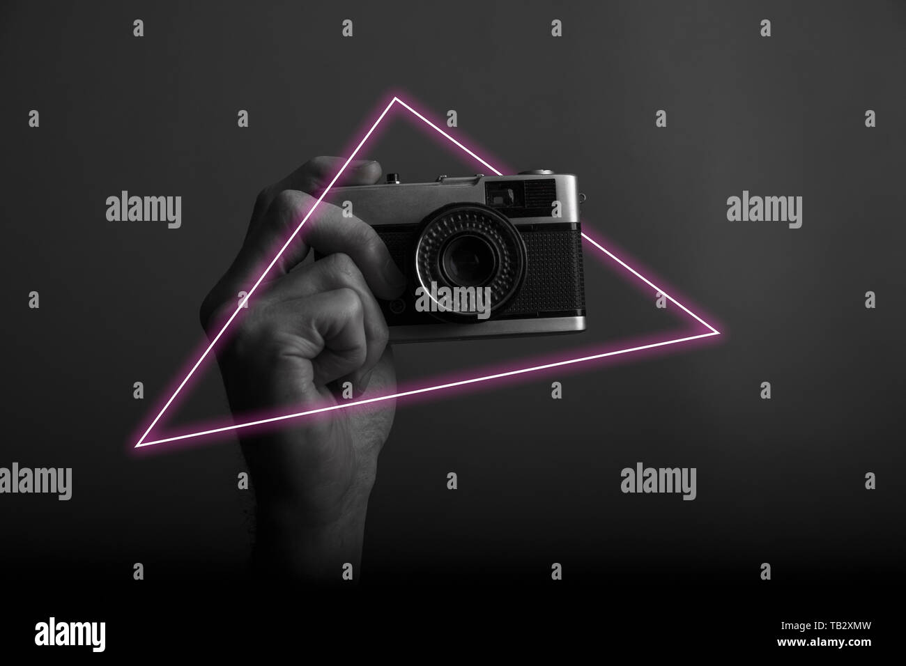 Male hand holding a vintage film camera with abstract neon light glow ...