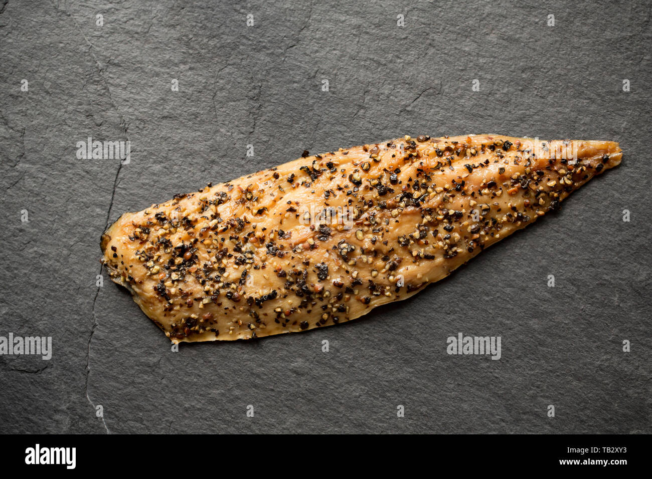 A Scottish hot smoked mackerel fillet, Scomber scombrus, with cracked black pepper bought from a supermarket in the UK. Mackerel are a source of Omega Stock Photo