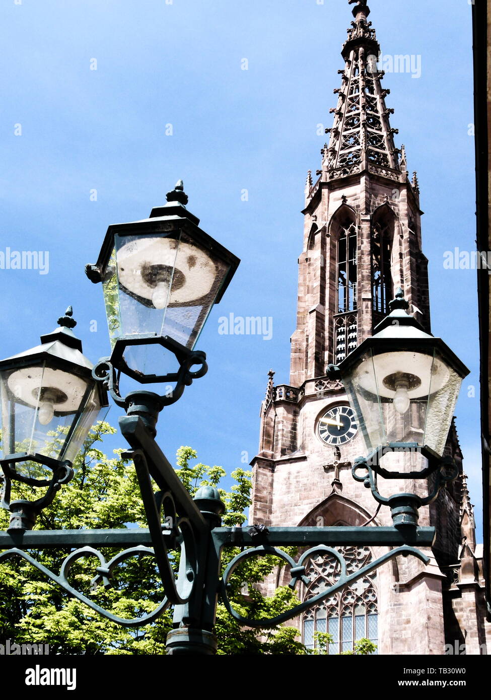 street lamp in retro style in front of neo-gothic church Stock Photo
