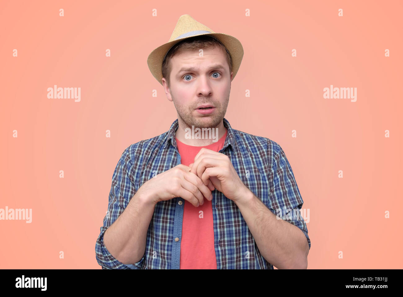 Shy young handsome man in summer hat is unsure Stock Photo