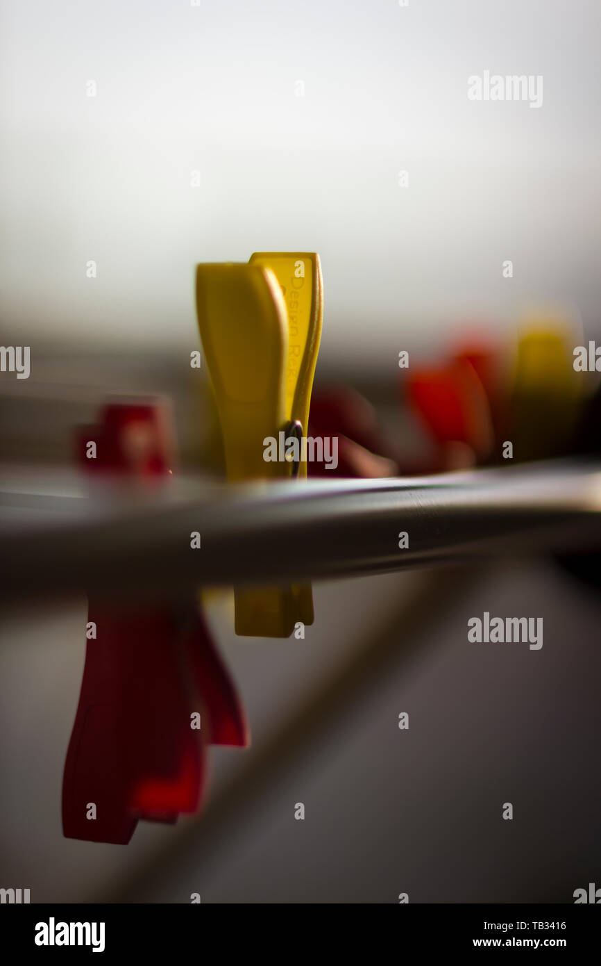 Re and yellow clothespins on loundry rack, upright format Stock Photo