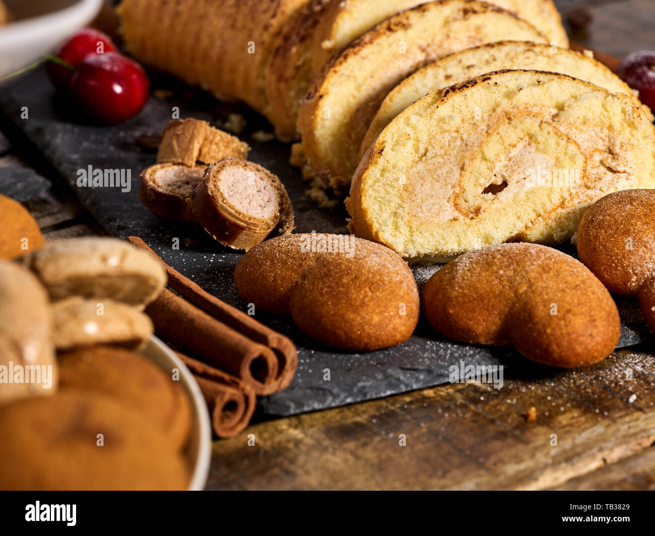 Sand cookies heart shape, rolled cake with cherry, cinnamon stick Stock Photo