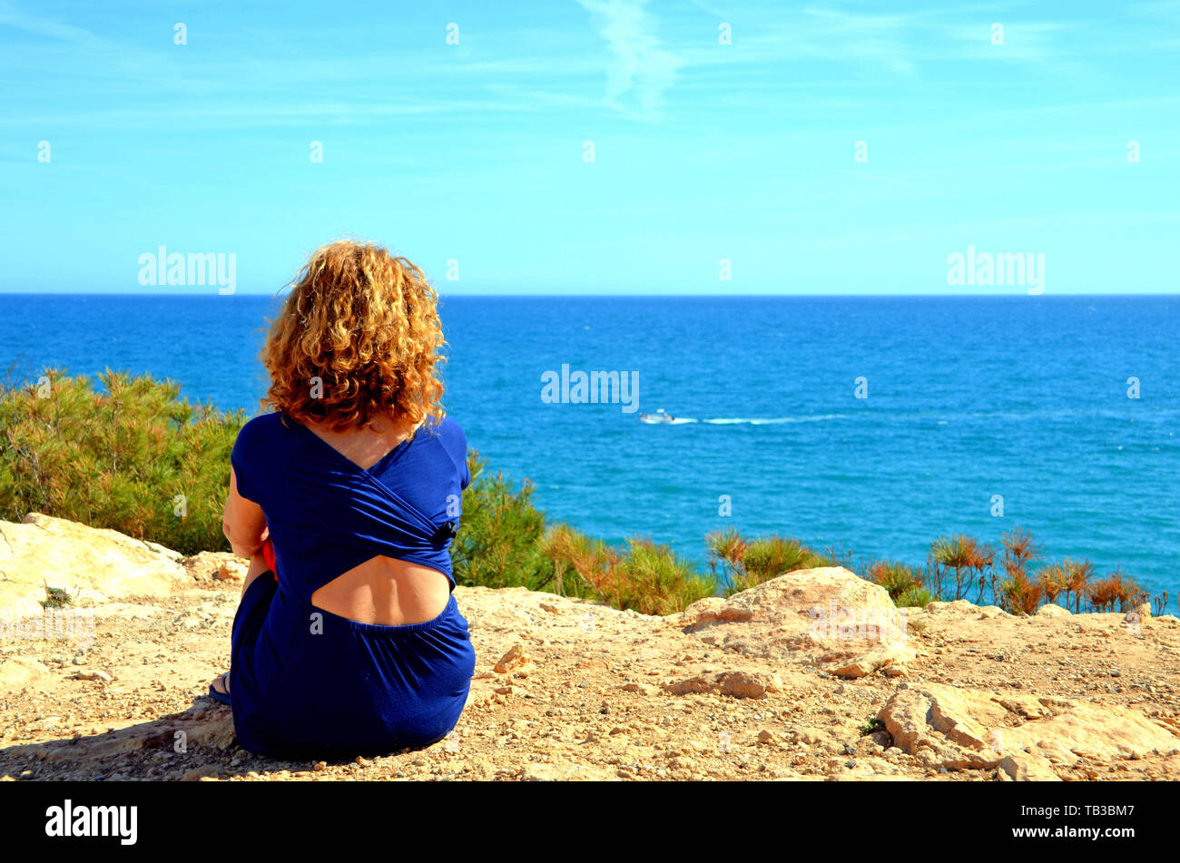 Curly-haired blonde woman looking at the sea in Torredembarra, Tarragona  Stock Photo - Alamy