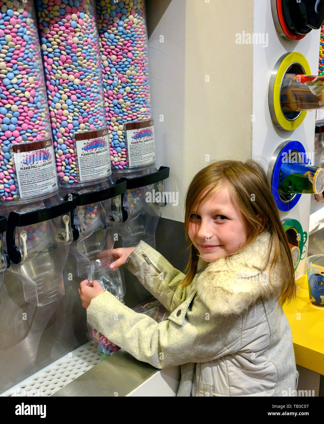 8 year old girl selects some sweets from a dispenser. Stock Photo