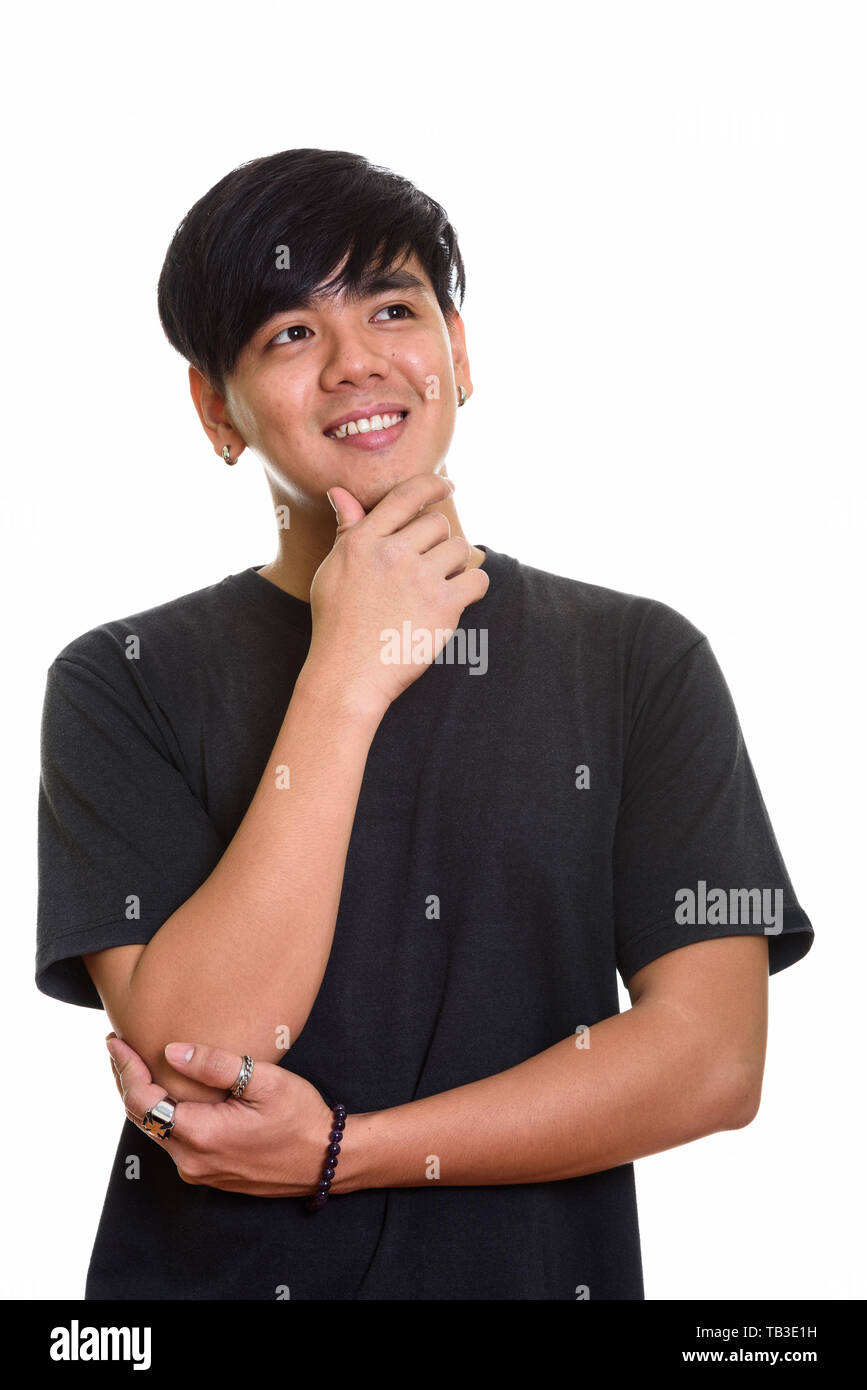 Studio shot of cool happy Asian man smiling while thinking Stock Photo