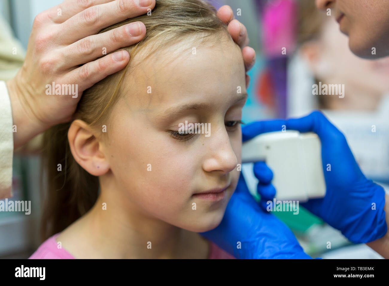 Girl pierced ear in the beauty salon. Adorable little girl having ear