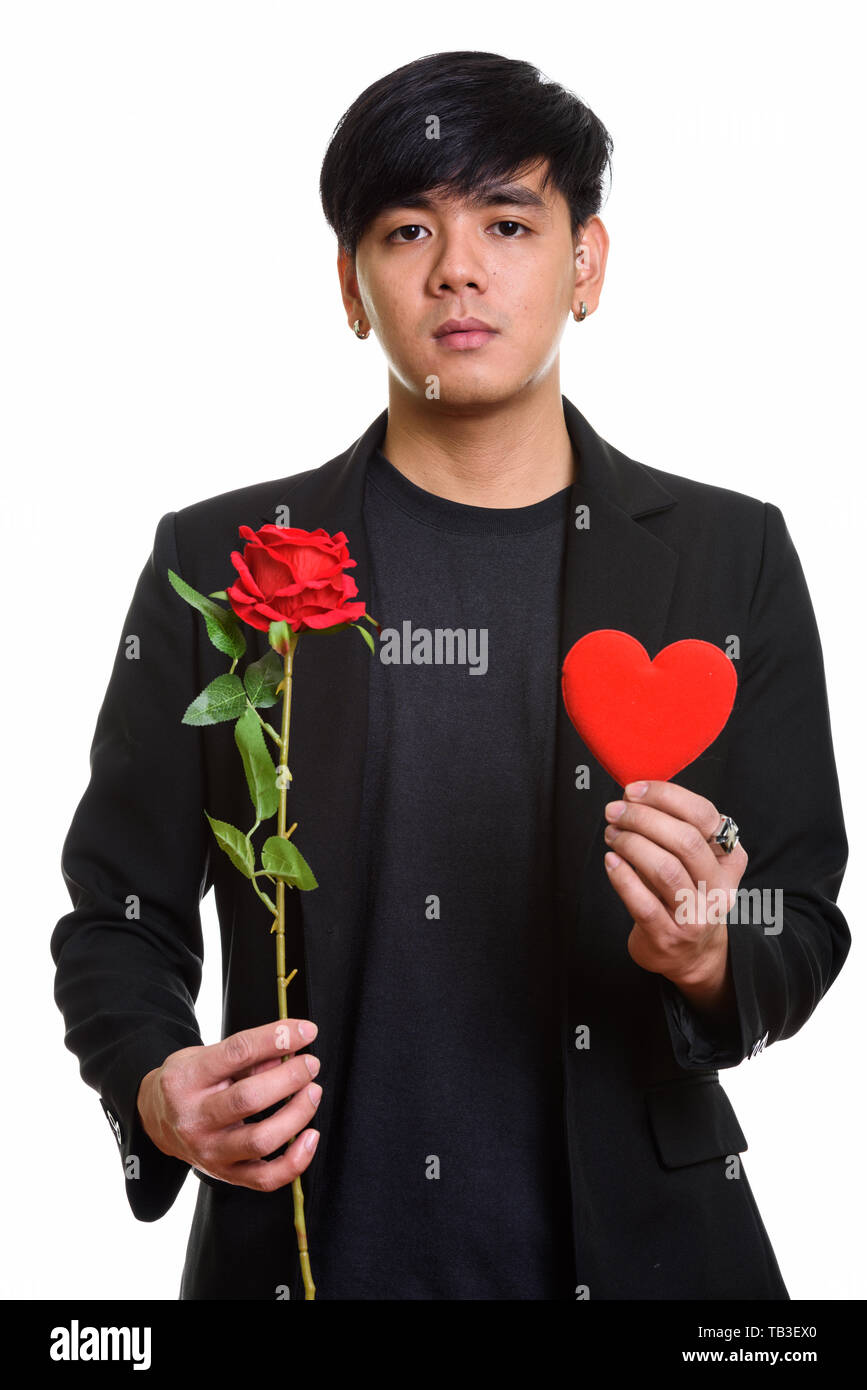 Studio shot of cool handsome Asian man holding red roses and hea Stock Photo