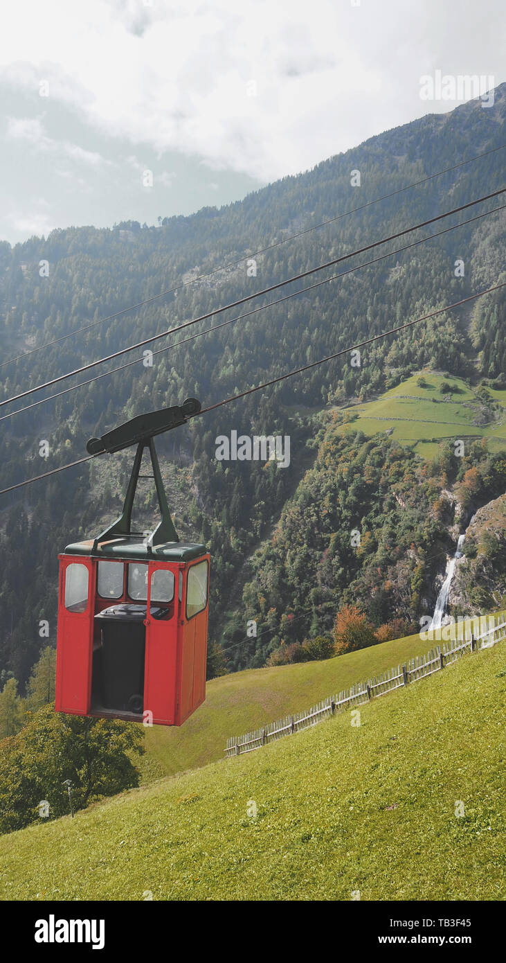 mountain cable car with rocks, green grass and waterfall in South Tirol ...