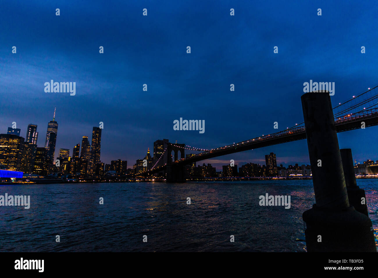 Skyline of the Brooklyn Bridge and modern skyscrapers of New York Financial District and the Lower Manhattan at night with marine monopile in New York Stock Photo
