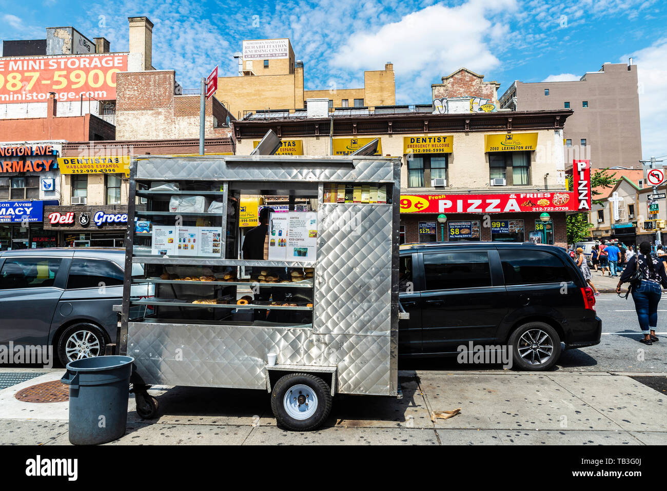 New York City, USA - July 31, 2018: Street food stalls of cookies, shops, farmacy, dentist, grocery and pizzeria with people around in Harlem, New Yor Stock Photo