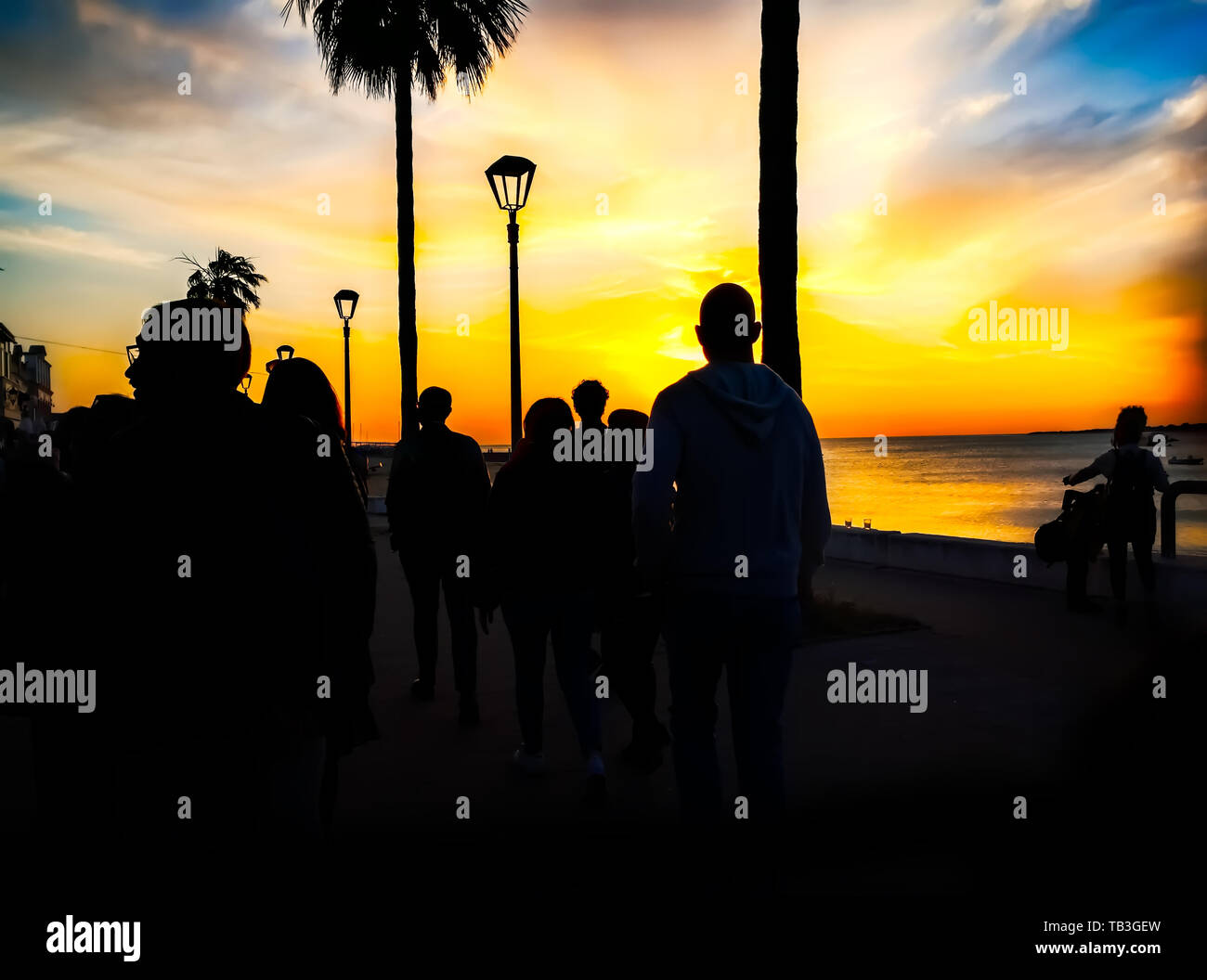 Silhouettes of people walking on the beach at sunset Stock Photo - Alamy