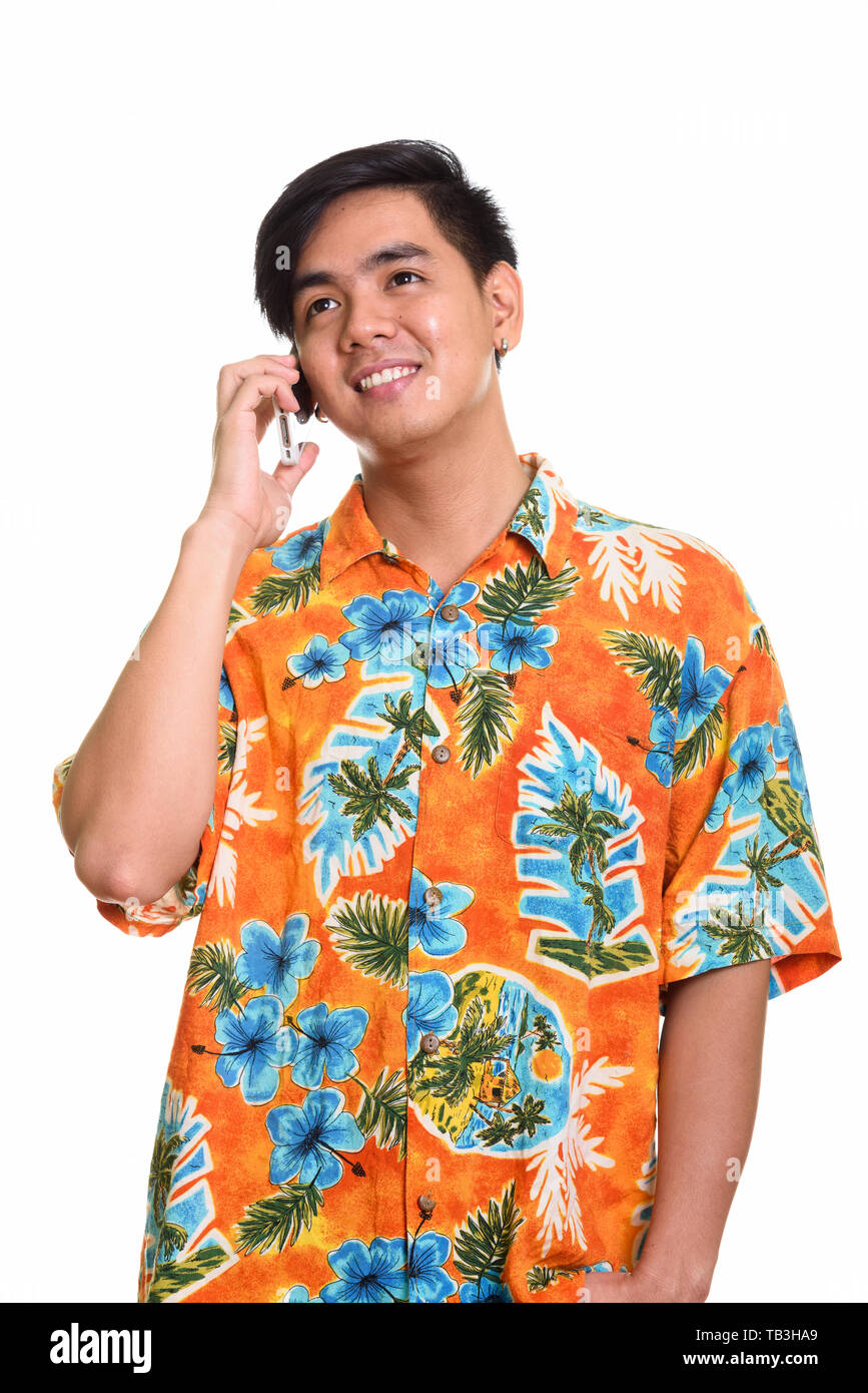 Young happy Asian man smiling and talking on mobile phone while  Stock Photo