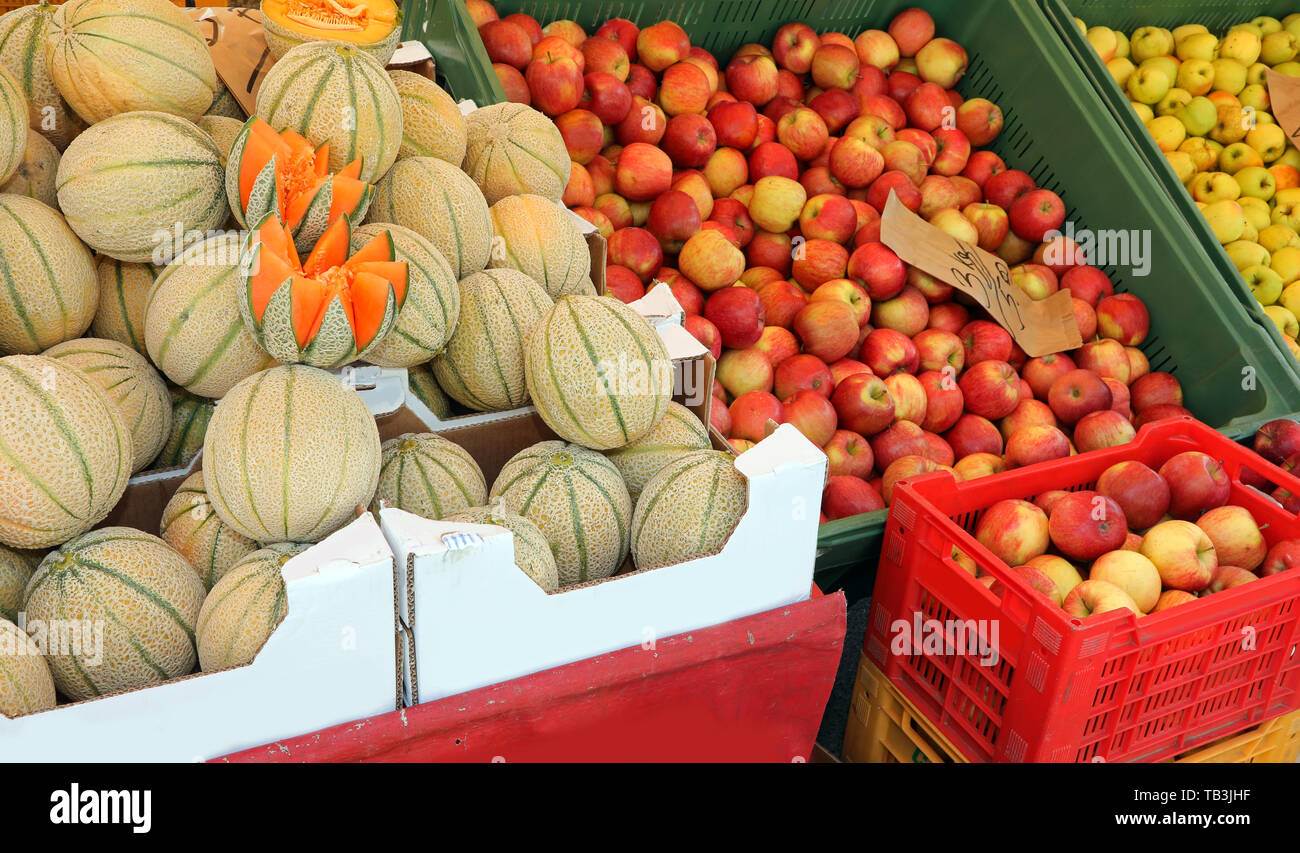 boxes full of apples and ripe melons in the stall of greengrocer Stock