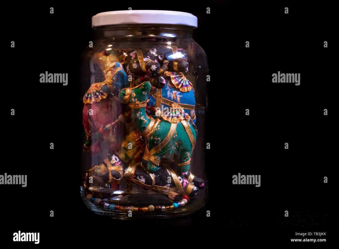 Colorful Israeli, middle-eastern souvenir, an artisan camel garland, stowed away in a jar for a showpiece at home. Isolated on a dark background. Stock Photo