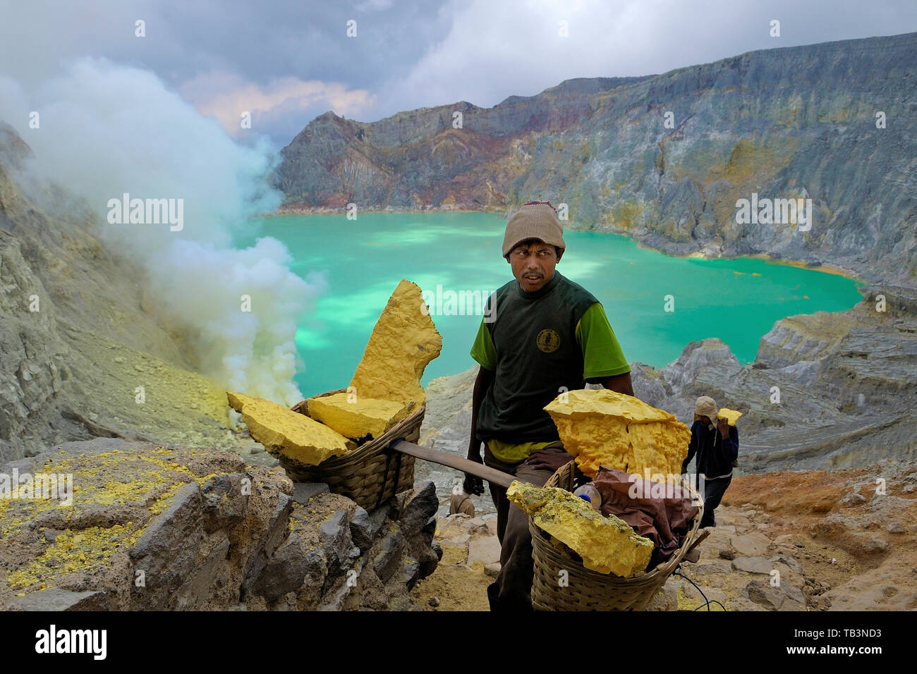 Arbeiter tragen schwere Schwefelsteine in Körben vom Vulkankomplex zur Basisstation, Kratersee Kawah eingebettet im Ijen-Krater, Kawah Ijen, Besuki, I Stock Photo