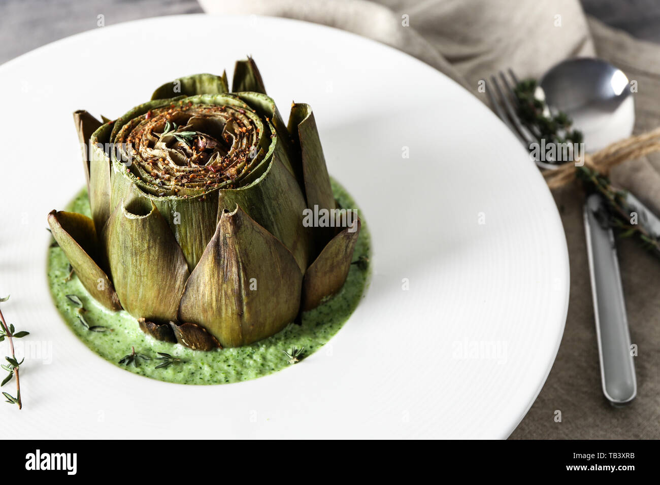 Plate with tasty cream soup and artichoke on table Stock Photo