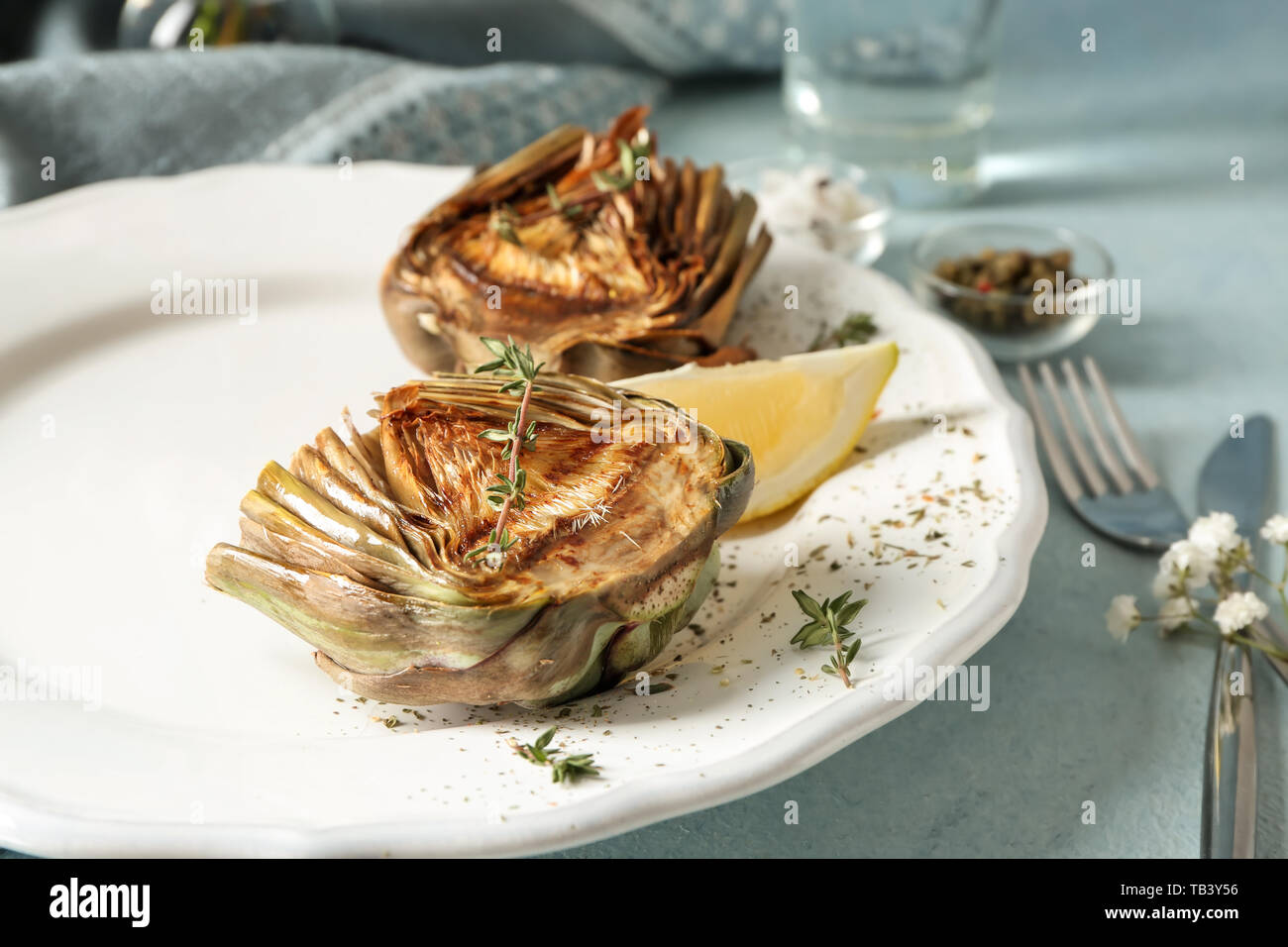 Plate with tasty grilled artichoke on table Stock Photo
