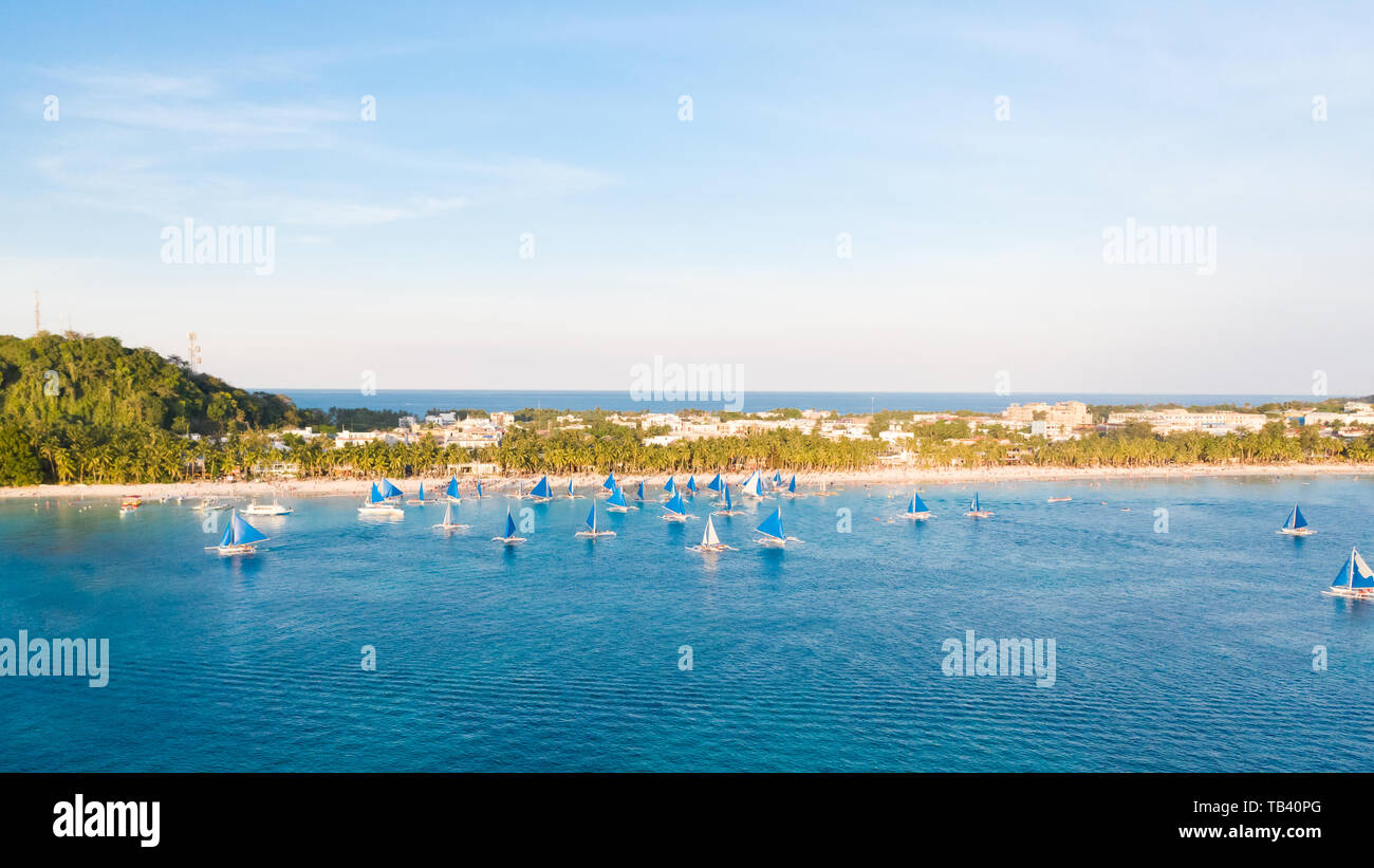 Small sailing boats for touristic excursions at sunset in Boracay island - Exclusive travel destination in Philippines. Blue sailboats on the island o Stock Photo