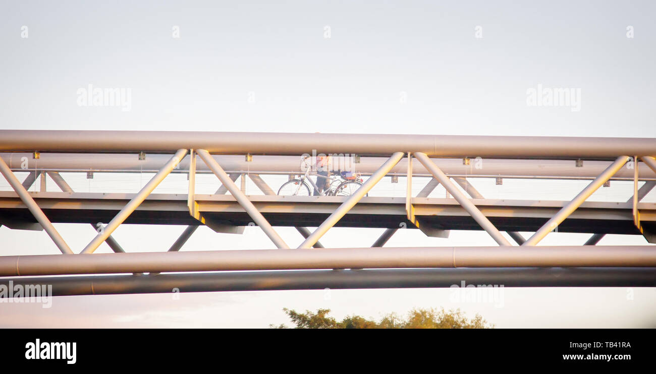 Metal-glass modern pedestrian crossing (suspension bridge) and cyclist Stock Photo