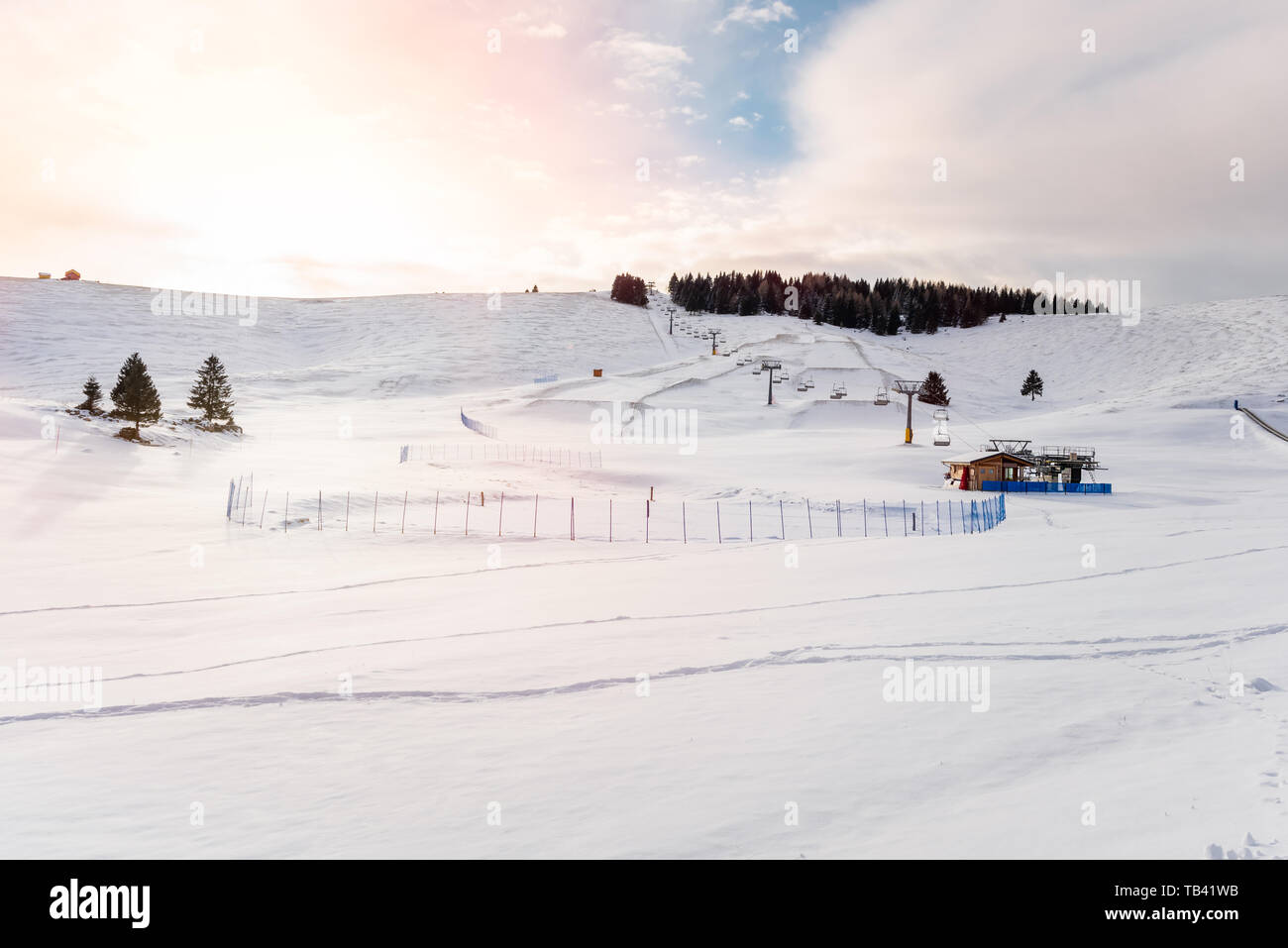 Snowy ski slopes and an empty chairlift in the Alps at sunset Stock Photo