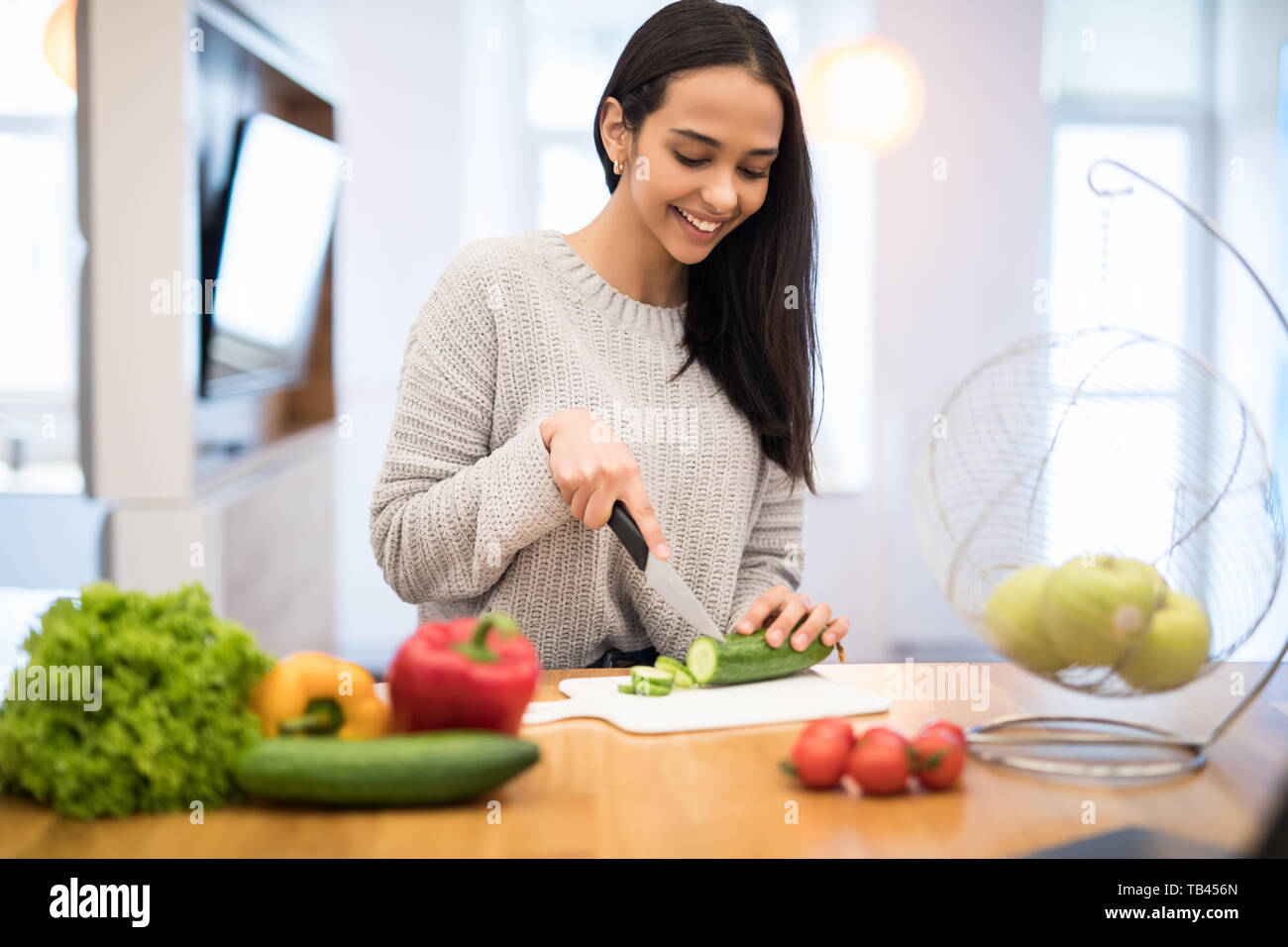 https://c8.alamy.com/comp/TB456N/the-young-woman-cuts-vegetables-in-the-kitchen-with-a-knife-and-laptop-on-the-table-vegetable-salad-diet-dieting-concept-healthy-lifestyle-cookin-TB456N.jpg